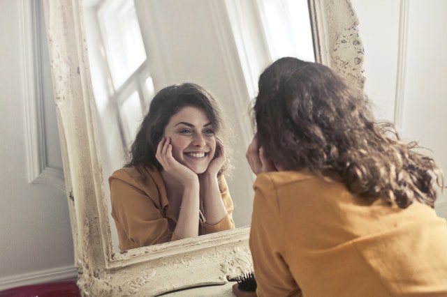 young woman smiling at reflection in mirror
